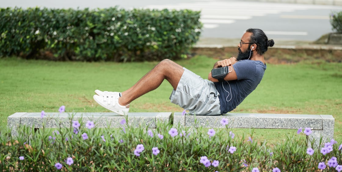 Young man in on a park bench doing sits up