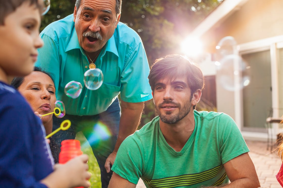 Three generation family playing with bubbles in backyard